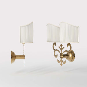 Neoclassical twin brass wall lamp with fleur-de-lis motif and symmetrical scrolls, white pleated shades, elegant Italian design - Finish: OBS Bronze Satin Brass