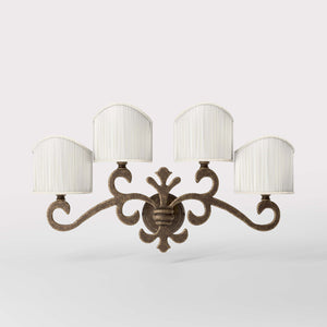Classical four-light brass wall lamp with central fleur-de-lis and decorative scrolls, white pleated shades, refined Italian design - Finish: OAS Antique Brass