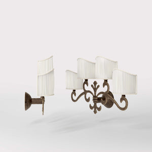 Classical four-light brass wall lamp with central fleur-de-lis and decorative scrolls, white pleated shades, refined Italian design - Finish: OAS Antique Brass