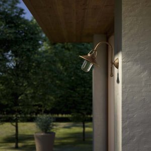 Outdoor brass wall lamp with curved arm protective hood and transparent glass diffuser rustic style Giada collection by Ghidini 1849 - Finish: OAS Antique Brass