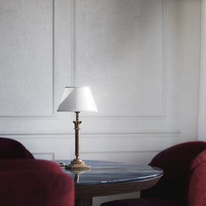 Classic brass table lamp with an ivory fabric shade, featuring an ornate column base, ideal for living rooms or office spaces by Ghidini 1849 - Finish: OAS Antique Brass