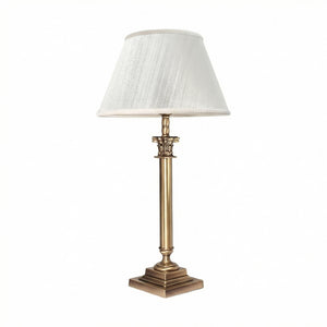 Brass table lamp with classic fabric shade in ivory white, decorative capital detail, ideal for elegant and timeless interiors