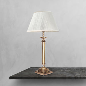 Brass table lamp with classic fabric shade in ivory white, decorative capital detail, ideal for elegant and timeless interiors