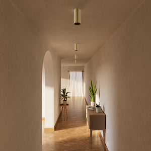 Cylinder ceiling lamp in brass with compact body installed on the ceiling of an elegant corridor by Ghidini 1849 - Finish: OBV Bronze Satin Light Brass
