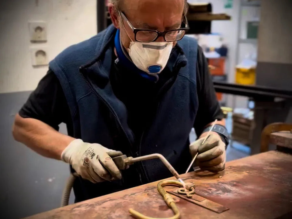 An artisan welding brass components in the Ghidini 1849 workshop