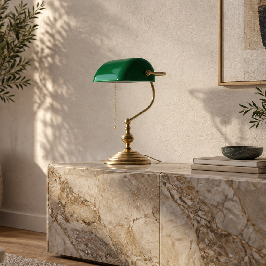 Ghidini 1849 banker’s lamp in bronze satin brass with a green glass shade on a veined marble sideboard in a contemporary living room
