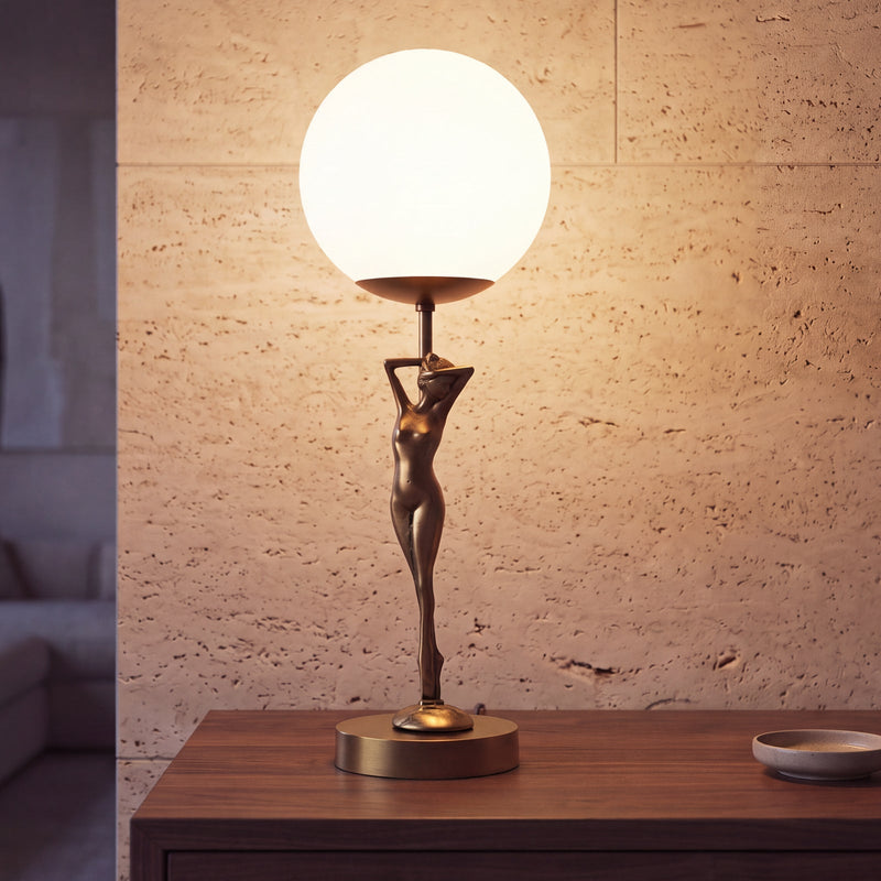 Lampada da tavolo Donne in ottone con scultura femminile e globo opale acceso su una credenza in noce.