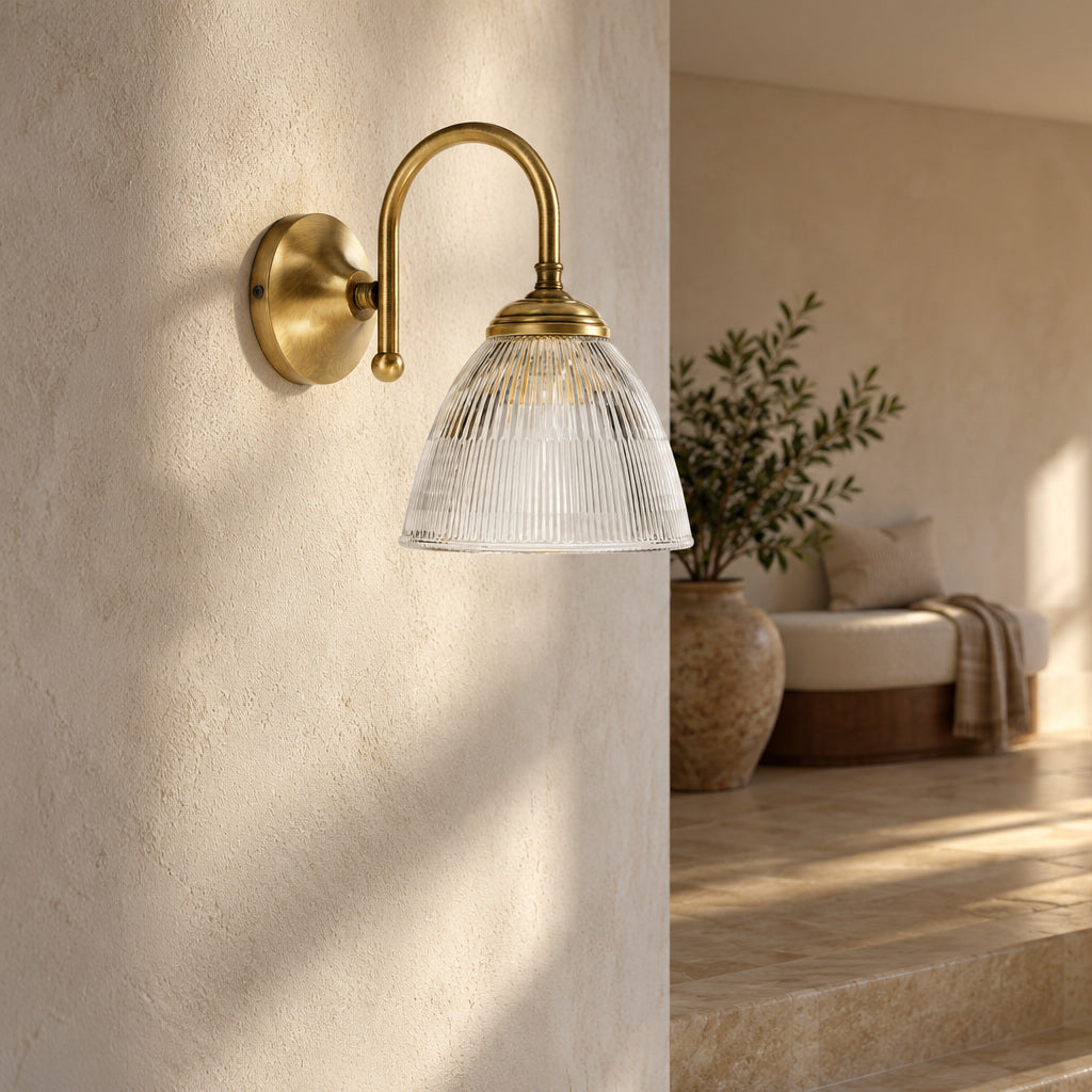 Elide brass wall light with an arched arm and ribbed glass bell high on an ivory stair-landing wall.