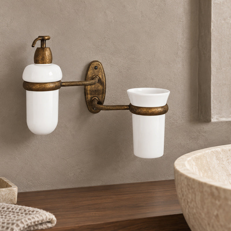 Emma wall set with a soap dispenser and ceramic tumbler on antique brass arms.