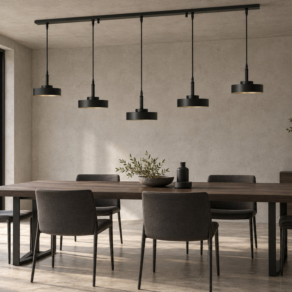 Mattschwarze Galaxias Pendelleuchte mit fünf Leuchten über einem dunklen Holztisch in einem minimalistischen Essbereich mit warmgrauem Stein und Metall.