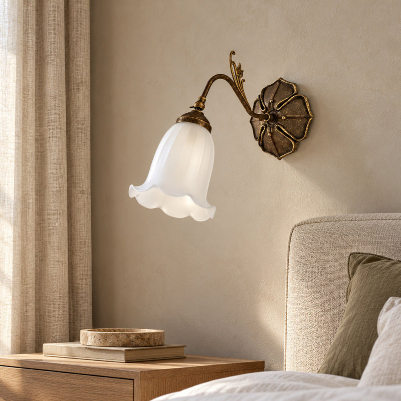 Mughetto wall lamp with a white bell-shaped glass shade above a linen headboard.