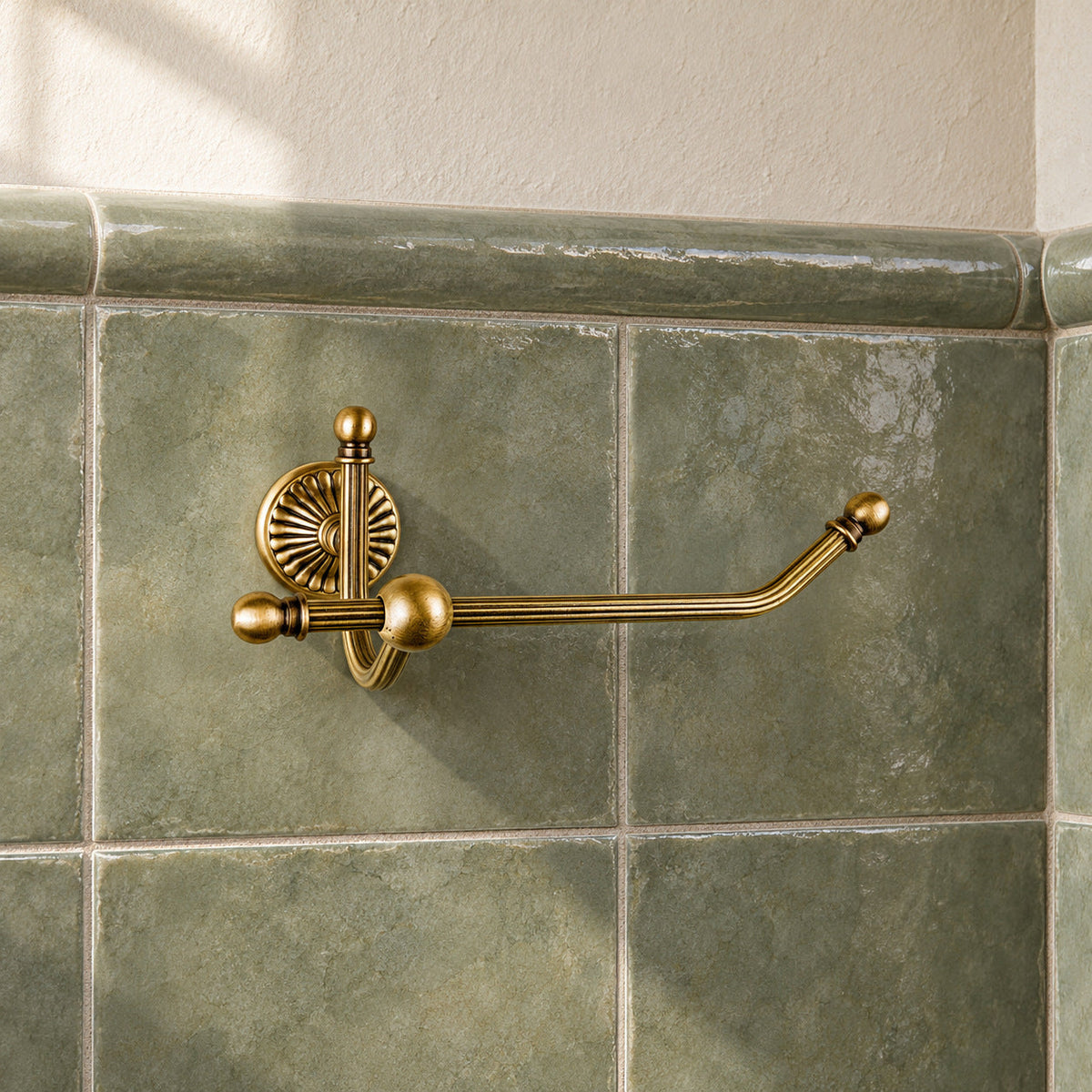 Leerer Dafne Toilettenpapierhalter in Satin Bronze an quadratischen, graugrün glasierten Fliesen