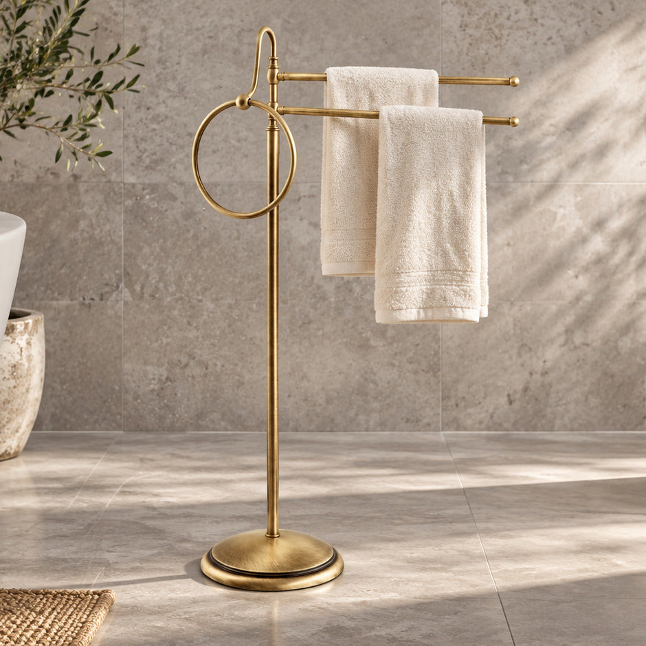 Freistehender Alba Handtuchhalter aus Messing in Satin Bronze mit zwei elfenbeinfarbenen Handtüchern neben einer Badewanne
