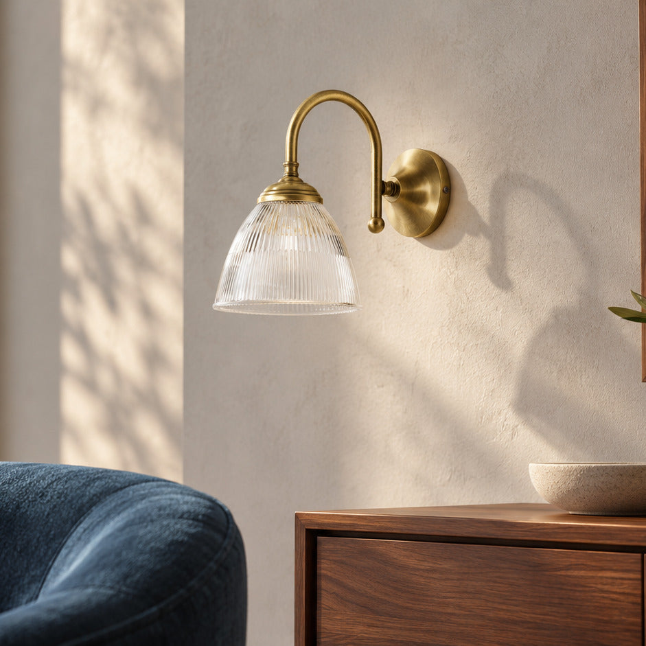 Applique Elide en laiton satiné et verre cannelé près d’un fauteuil bleu et d’un meuble en noyer