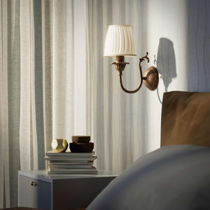 Classic brass wall lamp with pleated ivory white shade, decorative arm and floral details for elegant wall lighting - Finish: OAS Antique Brass