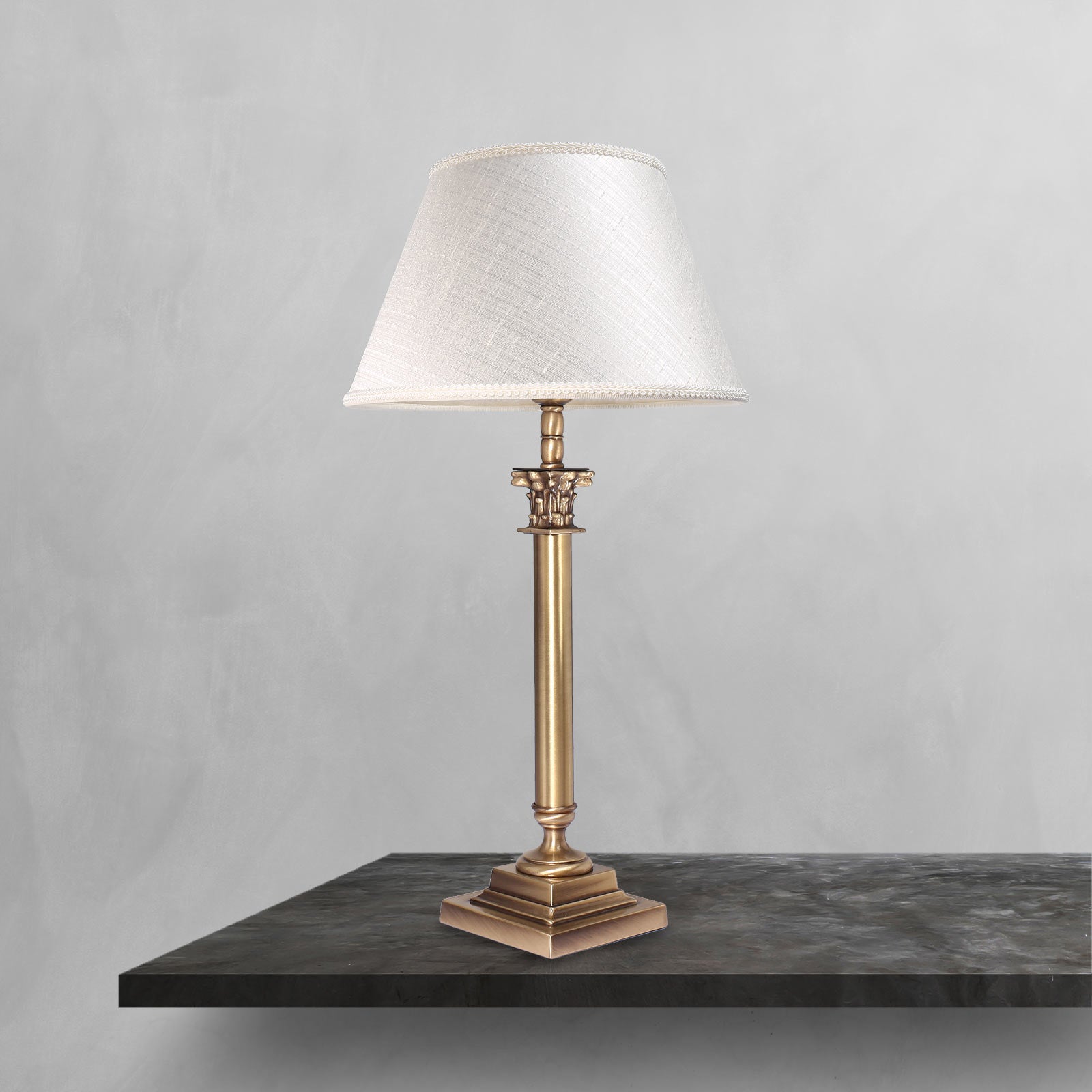 Brass table lamp with classic fabric shade in ivory white, decorative capital detail, ideal for elegant and timeless interiors