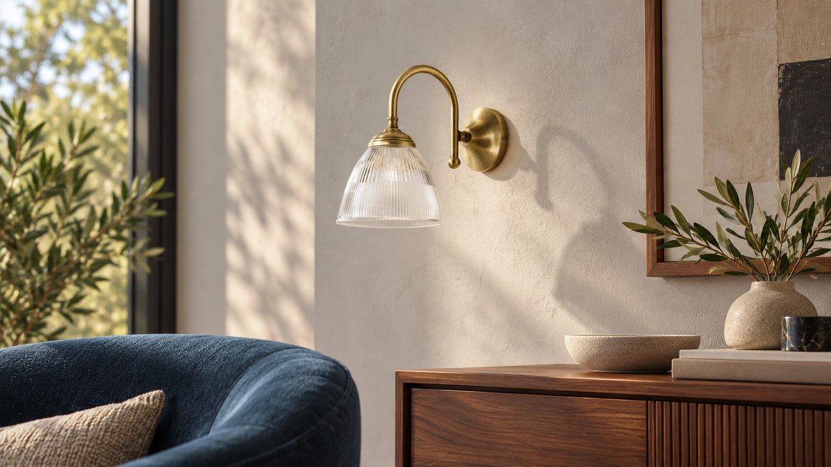 Applique Elide en laiton satiné et verre cannelé près d’un fauteuil bleu et d’un meuble en noyer
