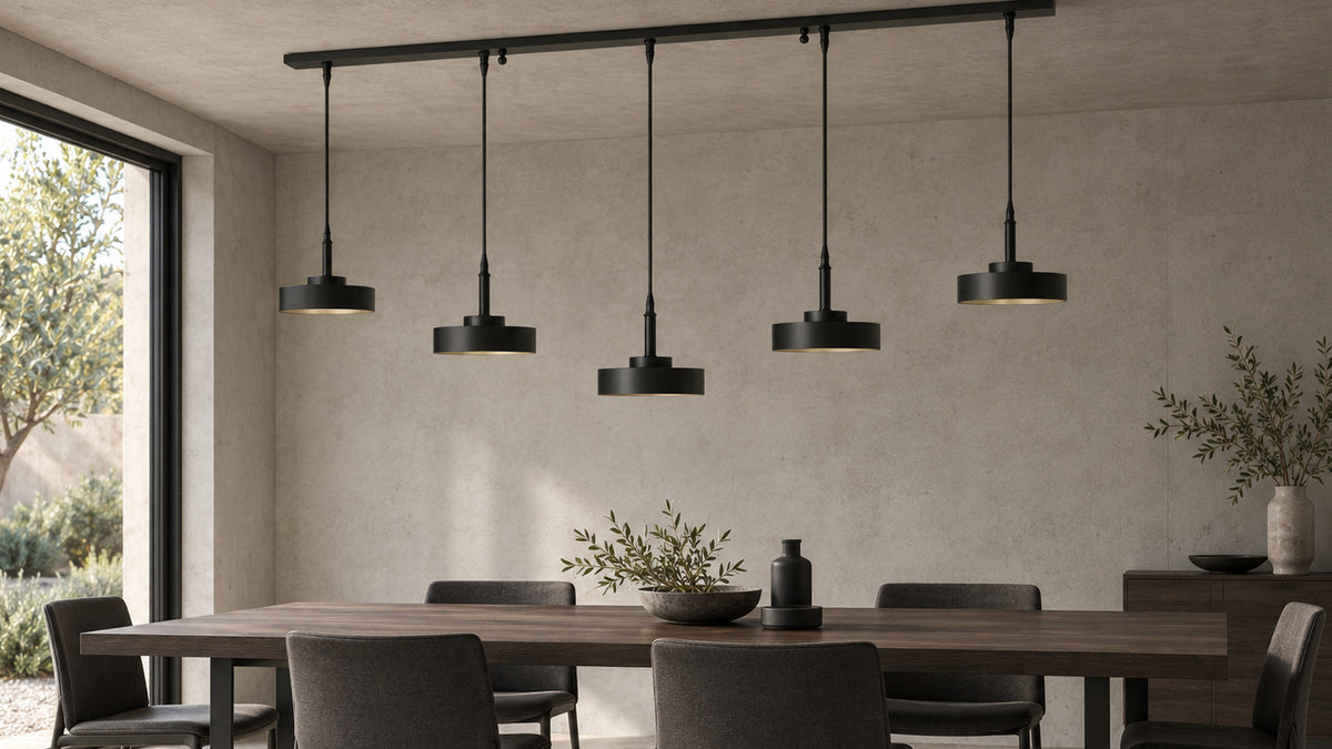 Mattschwarze Galaxias Pendelleuchte mit fünf Leuchten über einem dunklen Holztisch in einem minimalistischen Essbereich mit warmgrauem Stein und Metall.