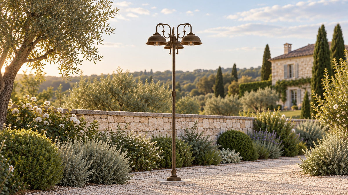 Lampadaire de jardin Lipari à trois lumières en laiton antique, près d'une allée de gravier et d'un mur de pierre