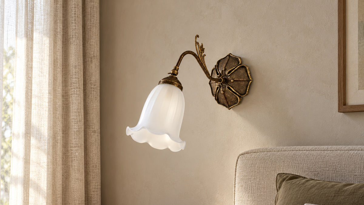 Mughetto wall lamp with a white bell-shaped glass shade above a linen headboard.