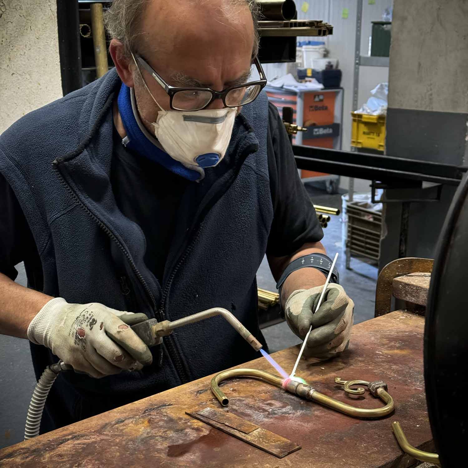 Italian artisan welds brass lamps components inside Ghidini 1849 factory