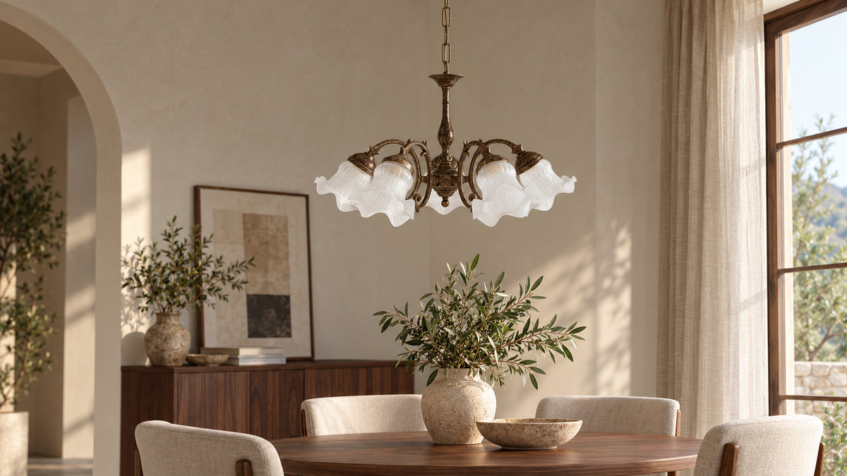 Lampadario Ricciolo in ottone anticato con cinque vetri bianchi a fiore sopra un tavolo rotondo in legno.